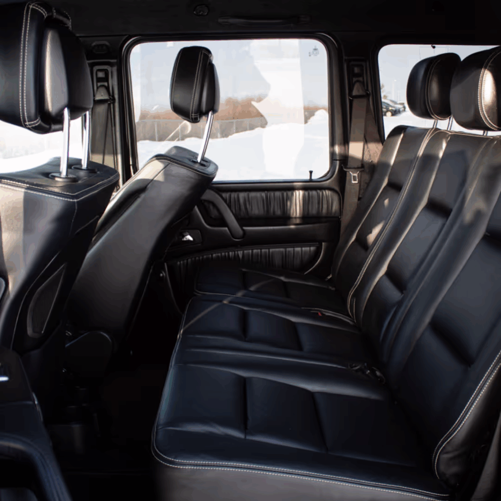Interior of a luxury SUV featuring spacious black leather seating, headrests, and large windows, showcasing a stylish and comfortable design ideal for passengers.