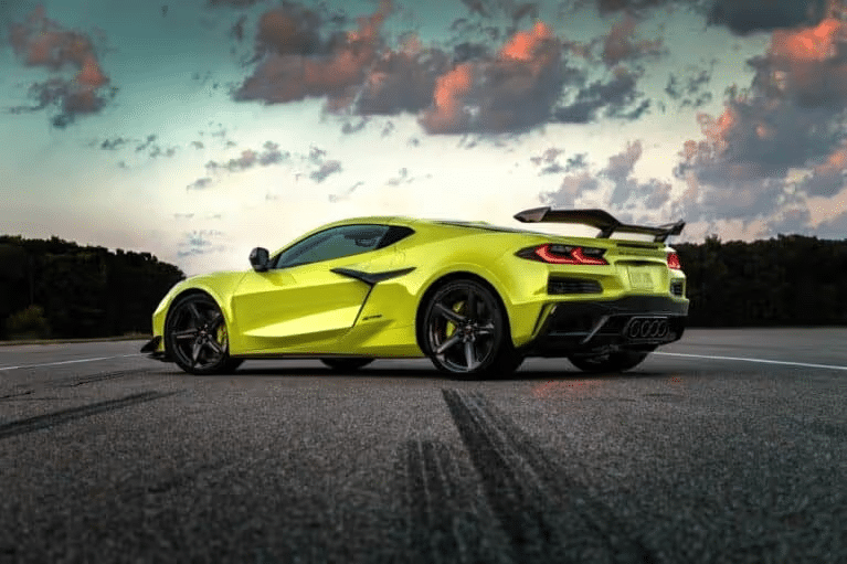 Bright yellow Chevrolet Corvette Z06 parked on a racetrack, showcasing its sleek design and aerodynamic features against a dramatic cloudy sky, highlighting the car's high-performance capabilities.
