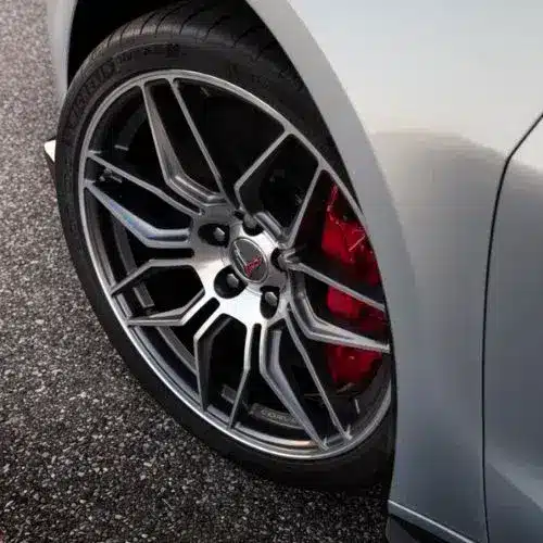 Four car tires displayed in a gradient setting, transitioning from a sunny environment to a snowy road, highlighting summer and winter tire tread patterns for optimal performance in varying weather conditions.