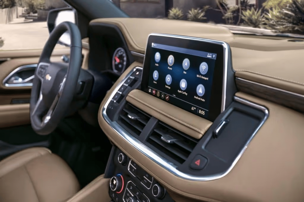 Interior view of a modern vehicle showcasing a touchscreen infotainment system, featuring navigation, audio controls, and smartphone integration options like Apple CarPlay and Android Auto, with a sleek dashboard design in beige and dark accents.