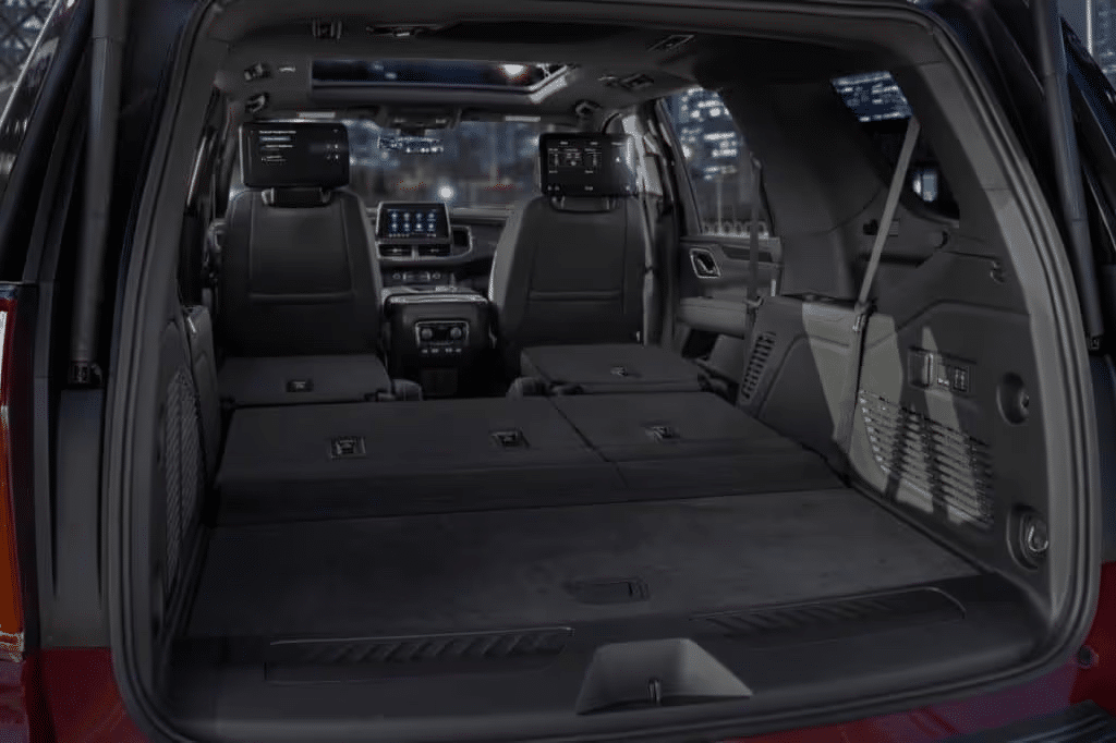Interior view of a spacious SUV with the rear seats folded flat, showcasing the expansive cargo area and advanced multimedia screens in the front seats, designed for family travel and entertainment.