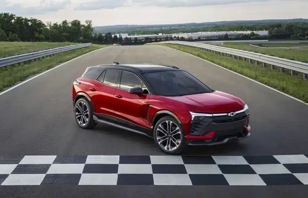 Sleek red Chevrolet SUV positioned at the finish line on a race track, showcasing its modern design and performance capabilities under a clear sky.