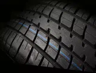 Close-up of a car tire showcasing the tread pattern and a blue stripe, emphasizing its design for traction and performance.