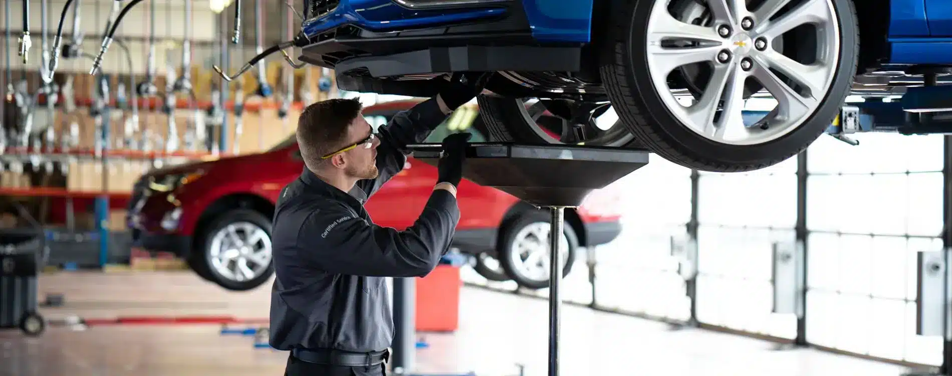 Automotive technician inspecting and servicing a car in a modern garage, with focus on vehicle maintenance and repair processes.
