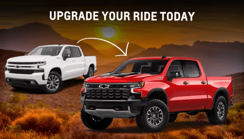 Alt text: Two Chevrolet trucks side by side, a white model and a red model, with a desert landscape in the background and the text "Upgrade Your Ride Today" overlaid at the top.