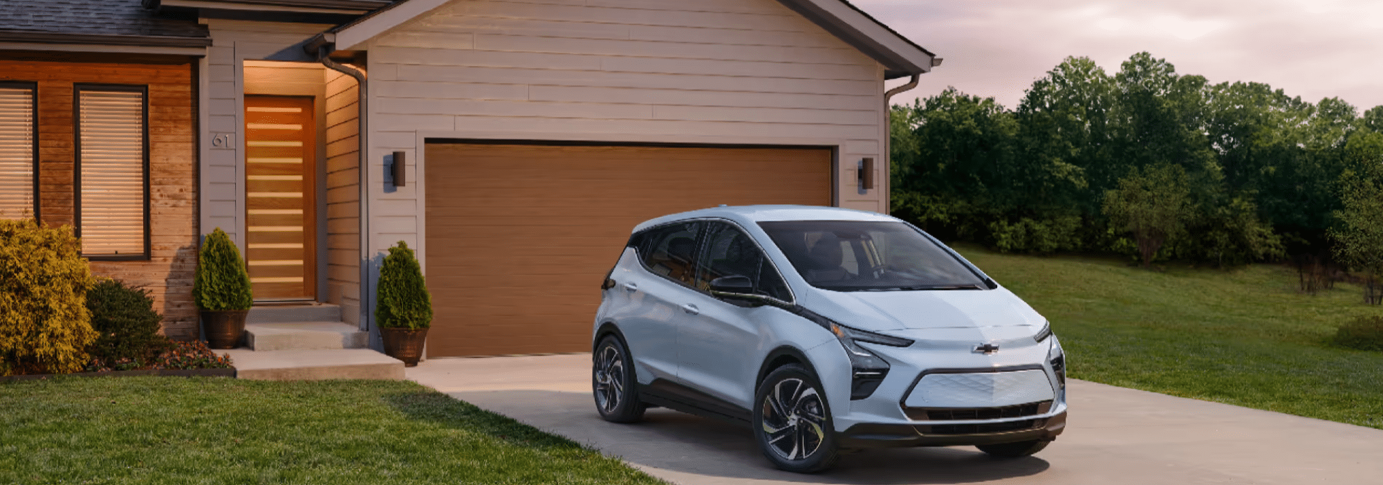 A Chevrolet Bolt EV parked in front of a modern home with a stylish wooden door and landscaped lawn, showcasing the blend of eco-friendly transportation and contemporary architecture.