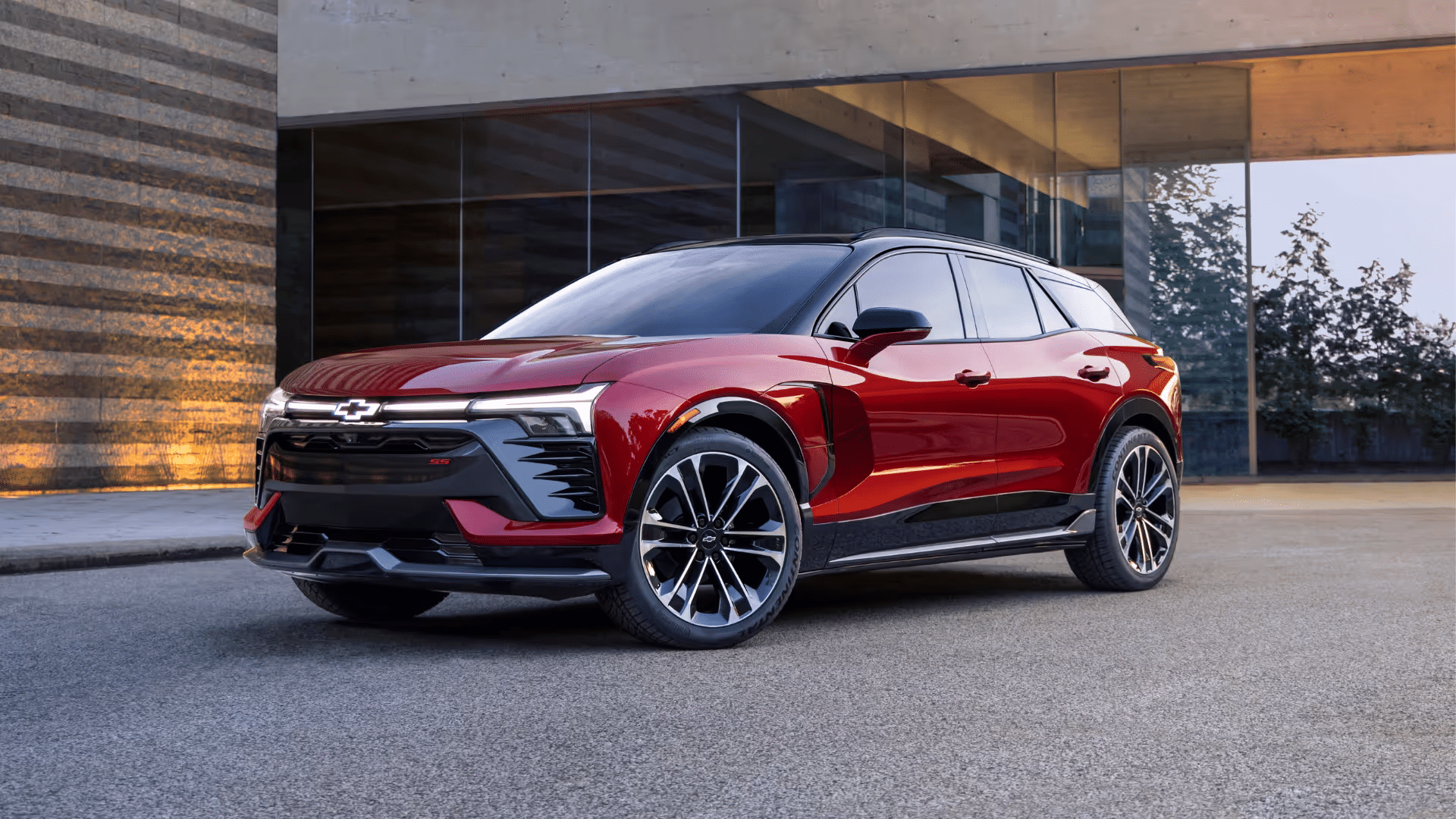 Sleek red Chevrolet SUV parked in an urban setting, showcasing its modern design and stylish features, with a reflective glass building in the background.