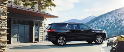 Black SUV parked in front of a modern cabin with a mountain backdrop, showcasing a scenic outdoor setting ideal for adventure and travel.