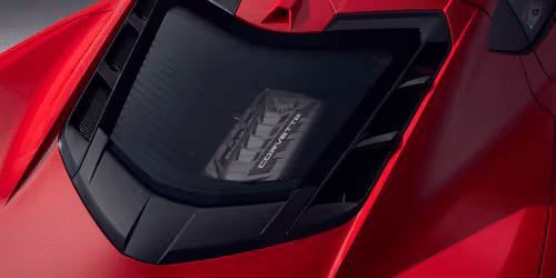 Close-up view of a red sports car's engine compartment showcasing a transparent cover revealing the high-performance engine, emphasizing advanced design and engineering features.