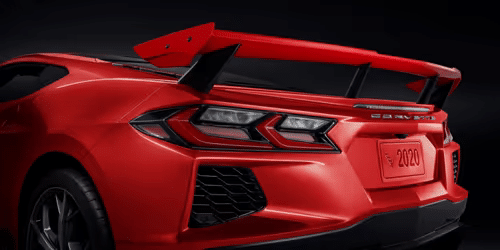 2020 Chevrolet Corvette C8 rear view showcasing its sleek design, distinctive taillights, and aerodynamic spoiler in a striking white finish.