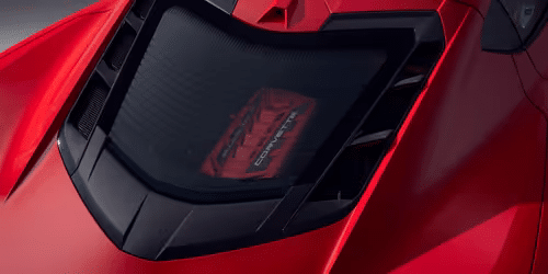 Close-up of a sleek red sports car engine cover showcasing its aerodynamic design and carbon fiber accents, highlighting the high-performance engineering beneath.
