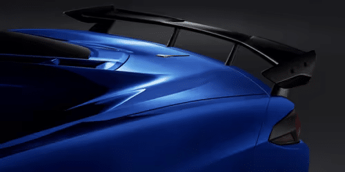 2020 Chevrolet Corvette C8 rear view showcasing its sleek design, distinctive taillights, and aerodynamic spoiler in a striking white finish.