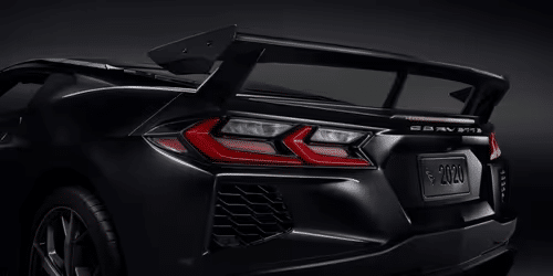 2020 Chevrolet Corvette C8 rear view showcasing its sleek design, distinctive taillights, and aerodynamic spoiler in a striking white finish.