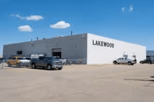 Exterior view of the Lakewood building featuring multiple parked trucks and a clear blue sky. Ideal for showcasing commercial properties and industrial facilities.