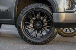 Black alloy wheel and rugged all-terrain tire on a modern pickup truck, showcasing a stylish and aggressive look suitable for off-road driving.
