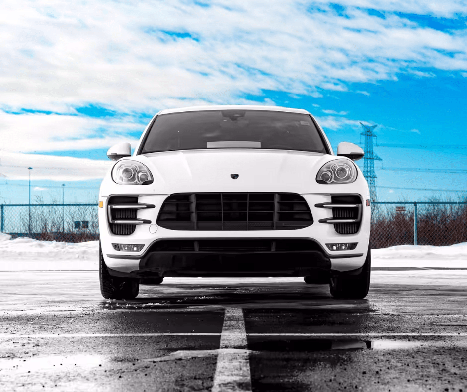 A sleek white luxury SUV parked on a snowy surface under a blue sky, showcasing its modern design and bold front grille.
