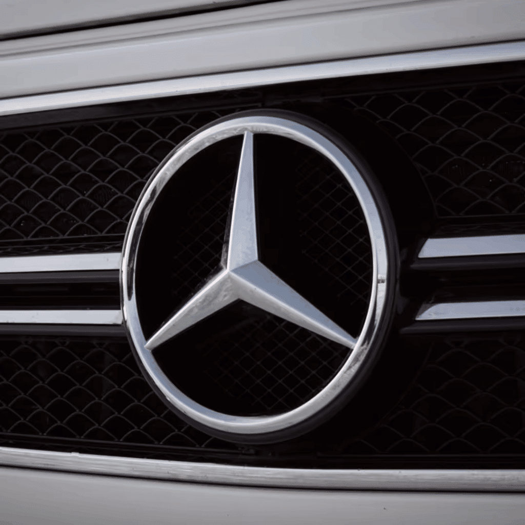 Close-up of the iconic Mercedes-Benz star logo prominently displayed on a vehicle's grille, showcasing its sleek chrome design and distinctive black mesh background.