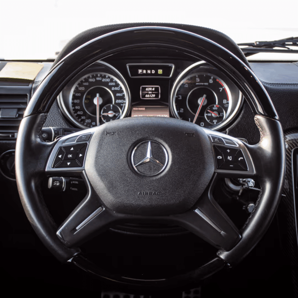 Interior view of a Mercedes-Benz steering wheel, featuring a sleek design, dashboard gauges, and control buttons for enhanced driving experience.