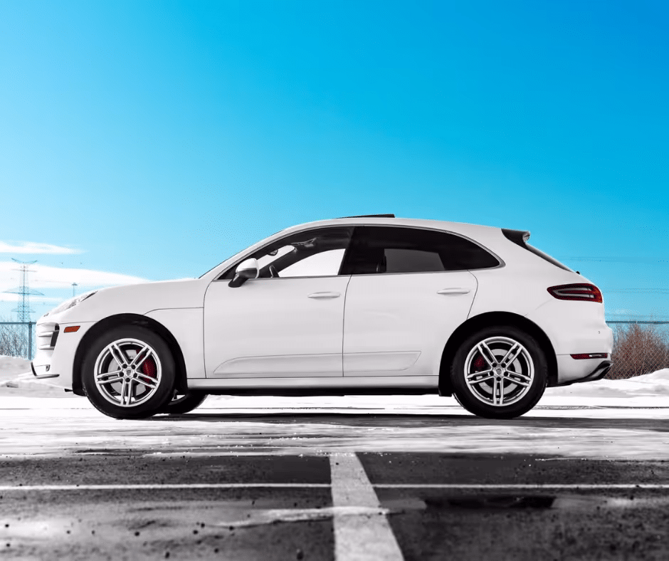Side view of a white luxury SUV parked on a snowy lot under a clear blue sky, showcasing its sleek design and alloy wheels, ideal for highlighting winter driving capabilities and premium automotive features.