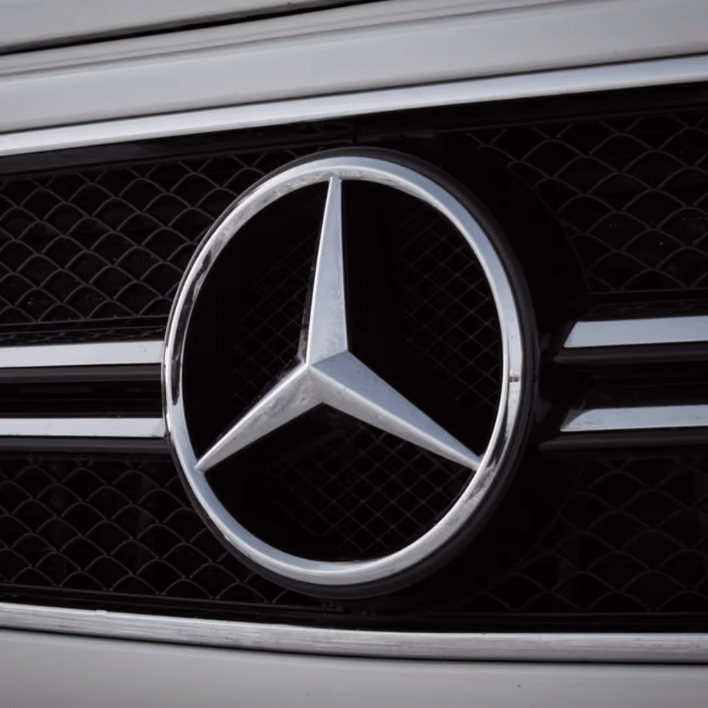 Close-up of the Mercedes-Benz emblem featuring the iconic three-pointed star, set against a sleek black grille. This image highlights the luxury and prestige associated with the Mercedes brand.