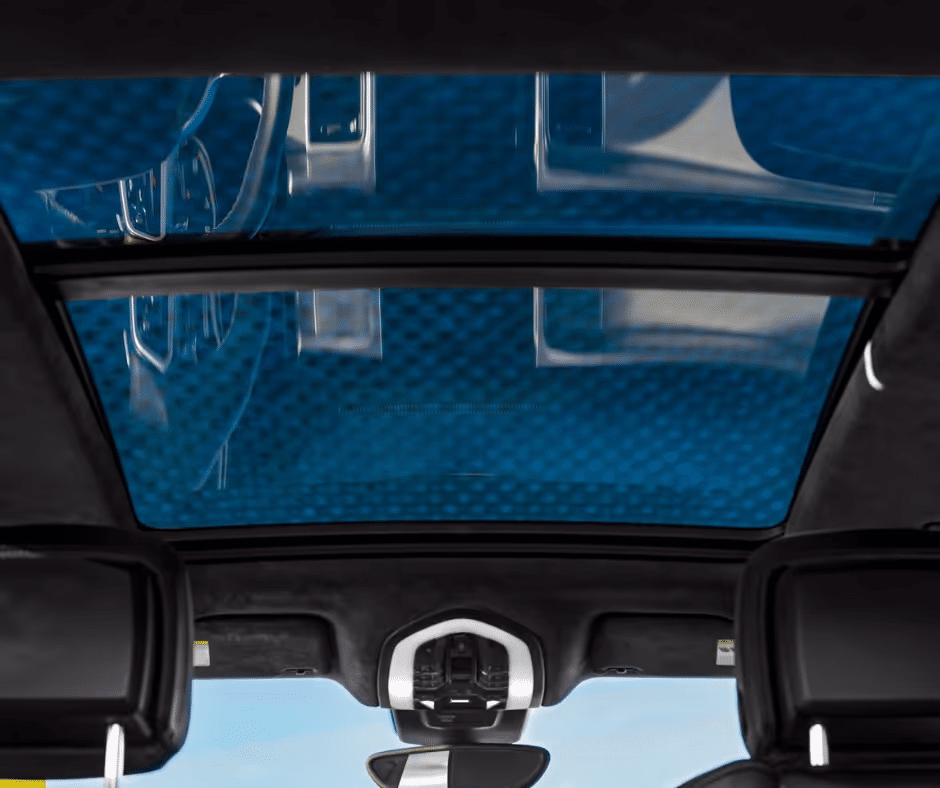 Interior view of a modern car featuring a panoramic sunroof, showcasing a blue-tinted glass ceiling and stylish black upholstery, highlighting the vehicle's luxury and spaciousness.