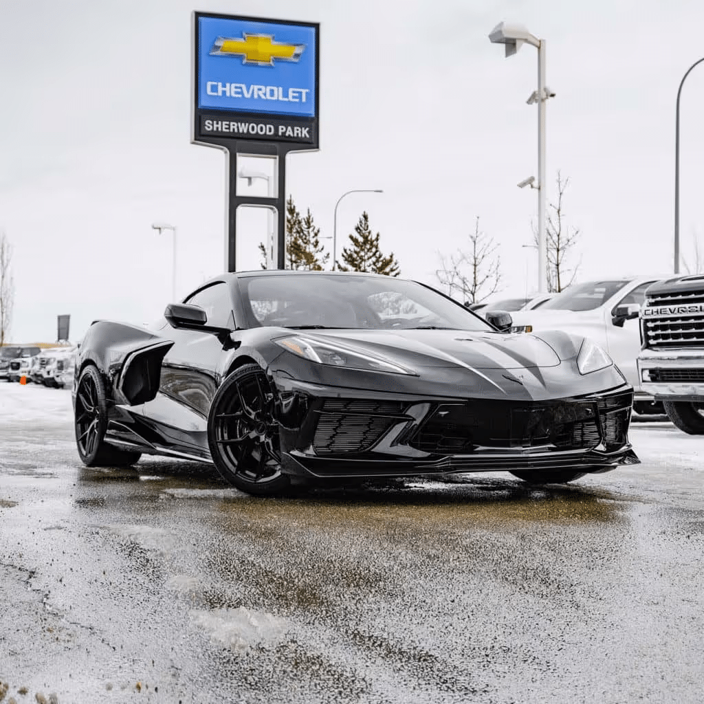Black Chevrolet Corvette C8 parked outside Sherwood Park Chevrolet dealership, showcasing sleek design amid snowy landscape.