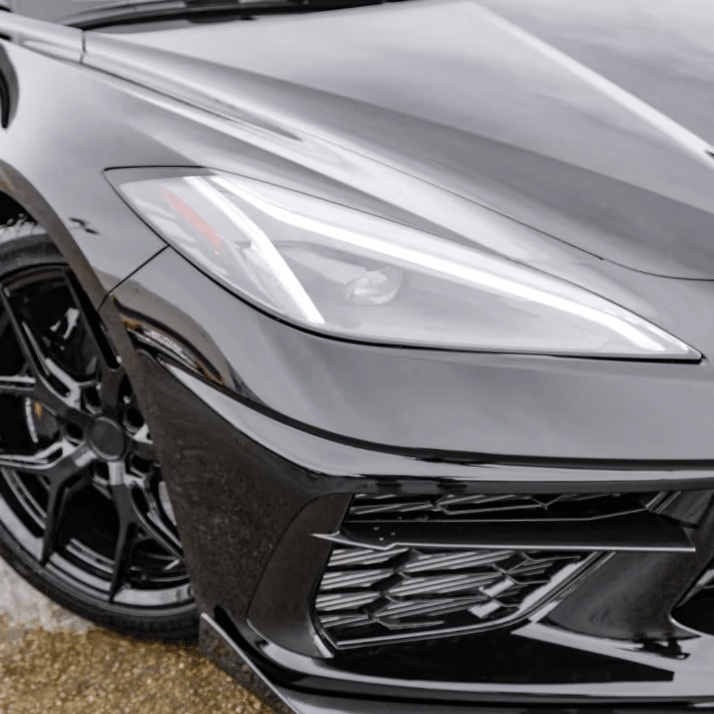 Close-up of a black Chevrolet Corvette C8 with sleek curves, advanced LED headlights, and aerodynamic features, showcasing its modern design and performance-focused aesthetic.