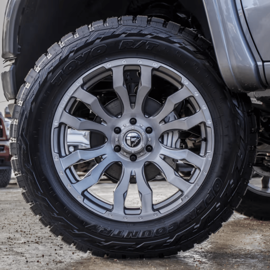 Close-up of a stylish silver alloy wheel mounted on a rugged Toyo Open Country tire, showcasing a blend of performance and aesthetics for off-road vehicles.