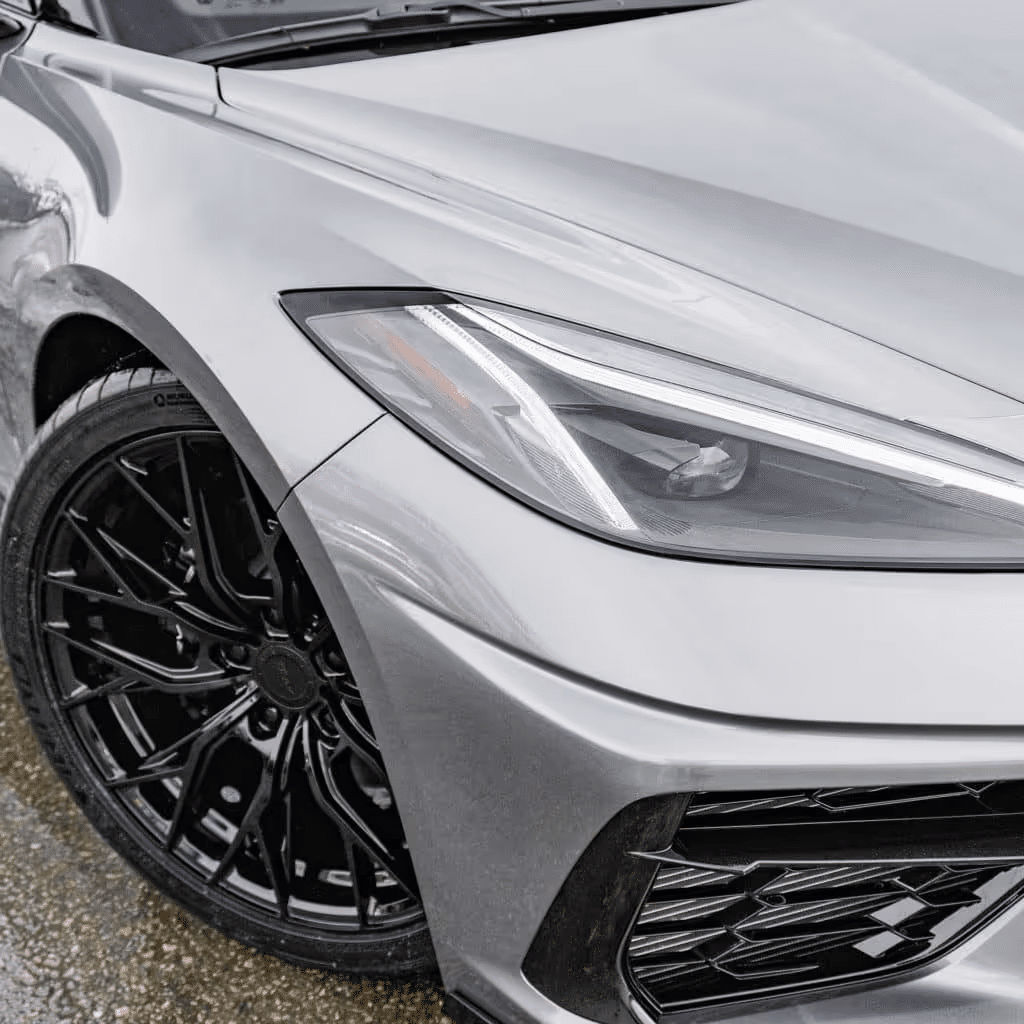 Close-up of a sleek silver sports car featuring a distinctive front design, modern headlights, and stylish black alloy wheels, emphasizing its performance and luxury appeal.