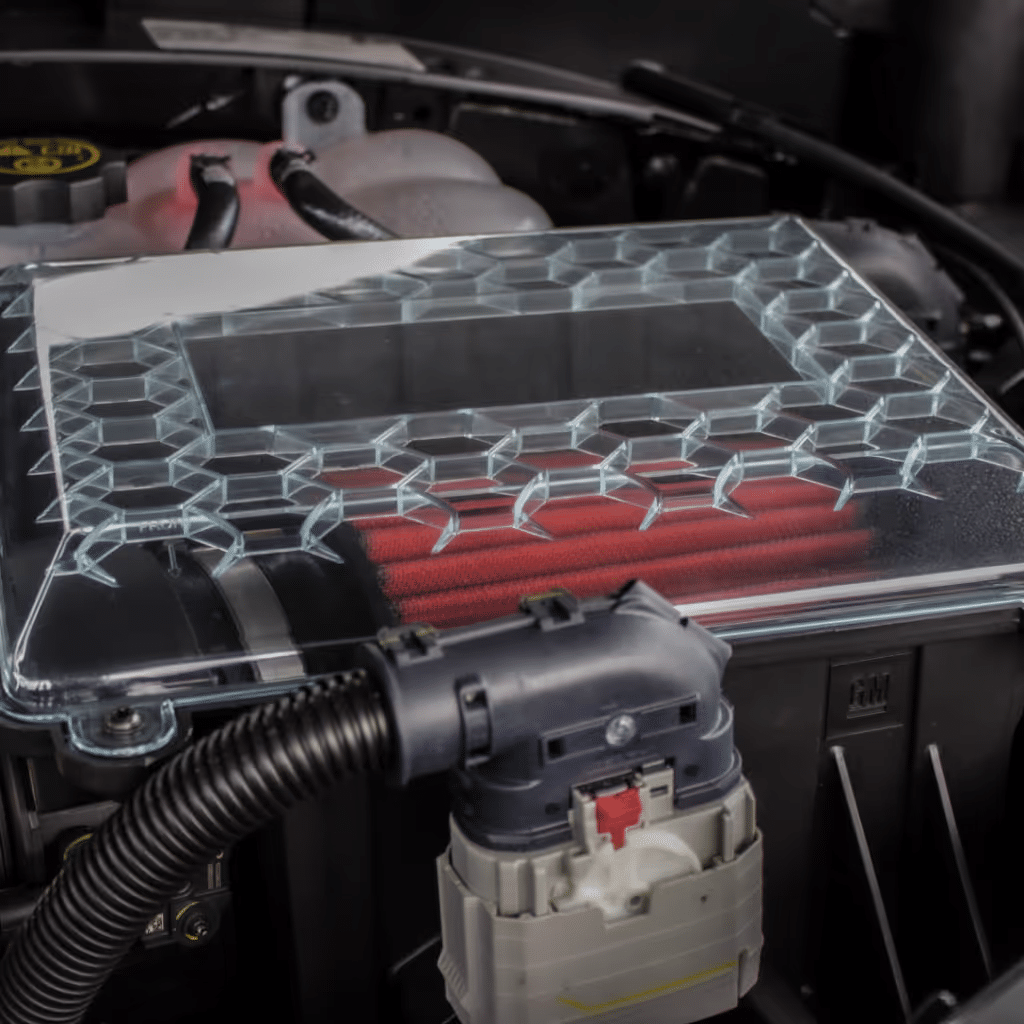 Clear engine air filter cover featuring a honeycomb design, highlighting red air filter elements, positioned within a car's engine bay for optimal airflow and performance.