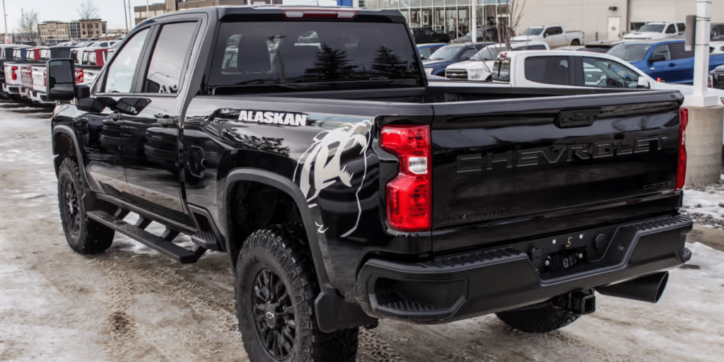Black Chevrolet truck with Alaskan design detail, displayed in a dealership lot. Features rugged tires and a sleek exterior, ideal for off-road adventures.