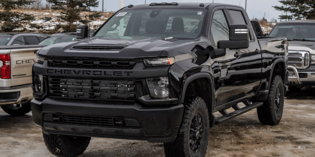 Black Chevrolet Silverado truck parked in a snowy lot, showcasing a bold front grille and rugged design suitable for tough terrains.