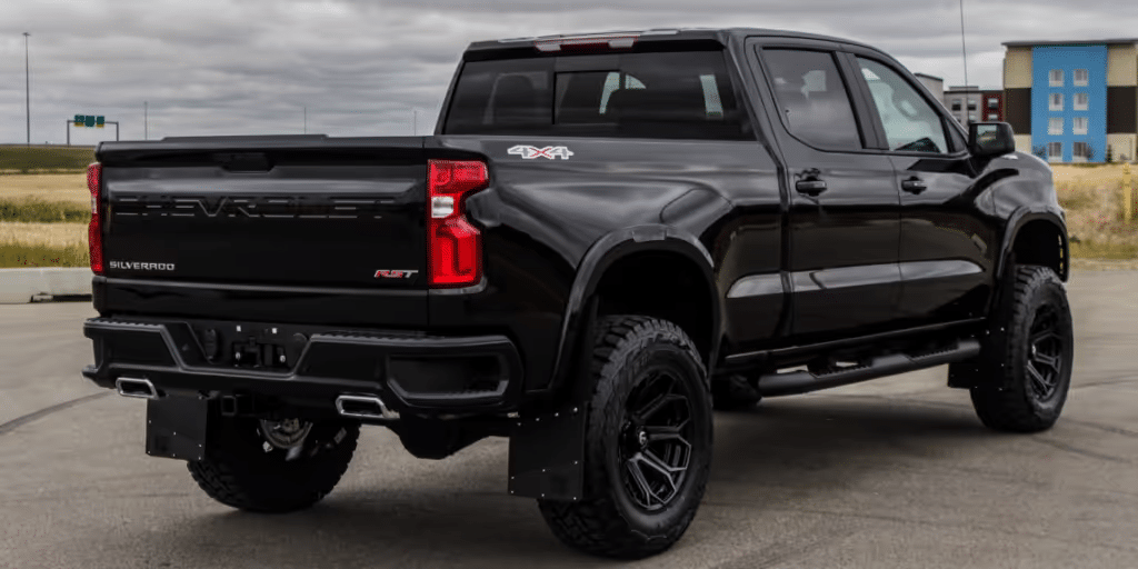 Black Chevrolet Silverado RST with off-road tires parked in an urban setting, showcasing its robust design and 4x4 capability.