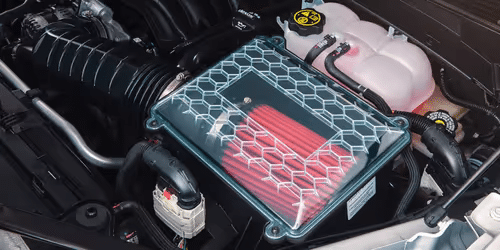 Close-up view of a car engine featuring a high-performance air filter with a hexagonal design, located near the intake system, showcasing red filter elements and surrounding components.