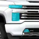 Detailed view of a white pickup truck front featuring distinctive turquoise accents on the bumper and headlights, showcasing a modern and stylish design.