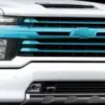 Front view of a white Chevrolet truck showcasing its distinctive blue grille and signature emblem, highlighting its modern design and style.