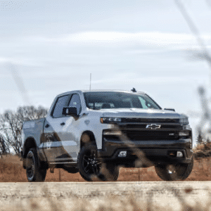 Chevrolet Silverado truck parked on a rural road with a clear sky in the background, showcasing its modern design and powerful build.