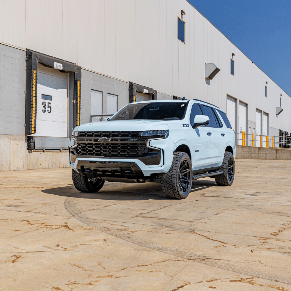 White SUV parked in an industrial loading dock area under a clear blue sky.