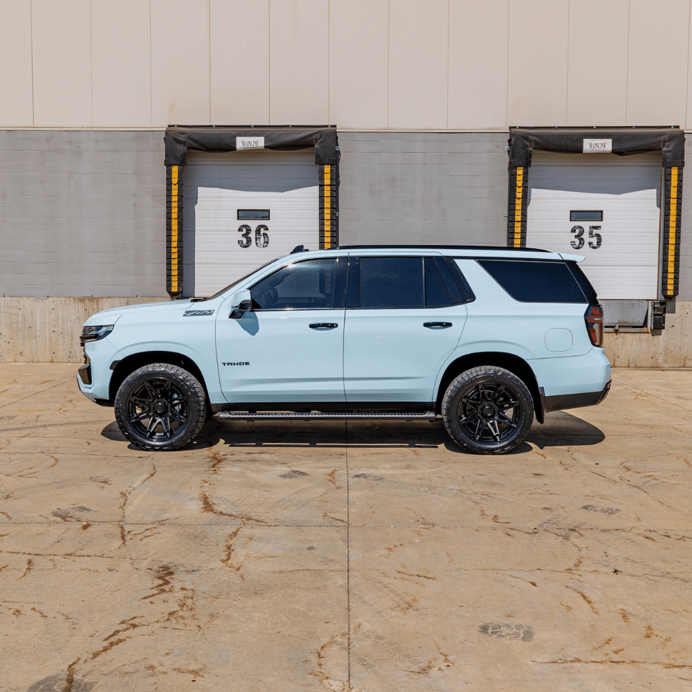 Light blue Chevrolet Tahoe parked in front of loading dock doors labeled 35 and 36.